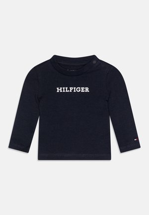 Marinblå långärmad skjorta i bomull, med vit "HILFIGER" text på framsidan, rund hals med tryckknapp och logodetalj på ärmen.