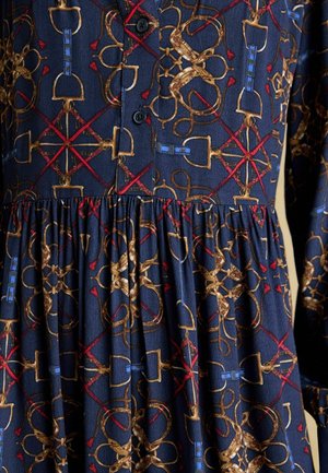 Navy dress featuring a textured fabric with gold and red abstract patterns, button closure, and gathered waistline.