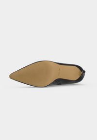 Chaussure noire à bout pointu montrée par la semelle, avec une semelle texturée beige et le nom de la marque ALDO.
