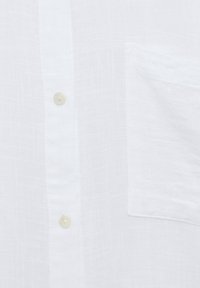 White linen button-up shirt featuring a front pocket, textured fabric, and round buttons for closure, highlighting a lightweight design.