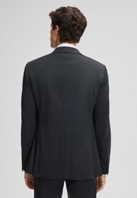 Giacca da abito grigio scuro con design elegante, vestibilità strutturata, texture sottile e spacco singolo sul retro, con quattro bottoni sui polsini.
