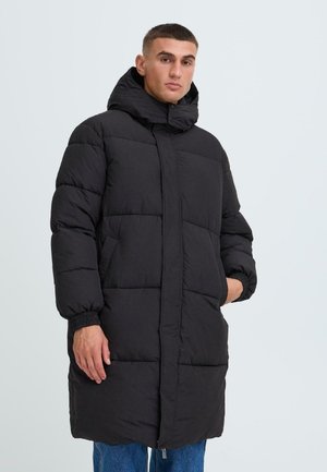 Zwarte gewatteerde jas met een lange snit, voorzien van een hoge kraag, rits sluiting en elastische manchetten. Gelaagd stof met doorgestikte panelen.