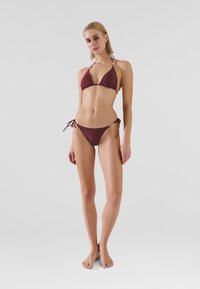 Burgundy színű bikini szett, triangel fazonnal és húzózsinóros alsó résszel, sima anyagból, minimális hardver díszítéssel.