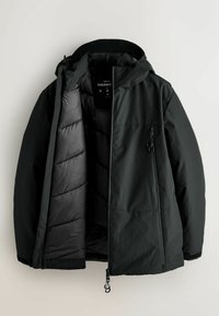 Mustal outerwear jakk, millel on kapuuts, esi lukuga, elastsed mansetid ja paks vooder soojendamiseks. Lukuga tasku detail.