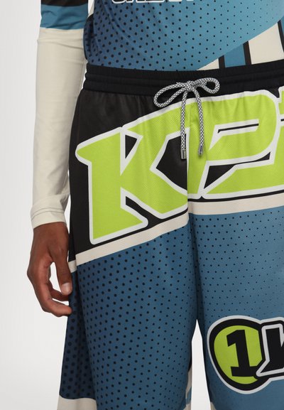 Blå og sorte atletikshorts med stort grønt "K"-grafik, snørelukning og meshtekstur med prikmønstre og store accenter.
