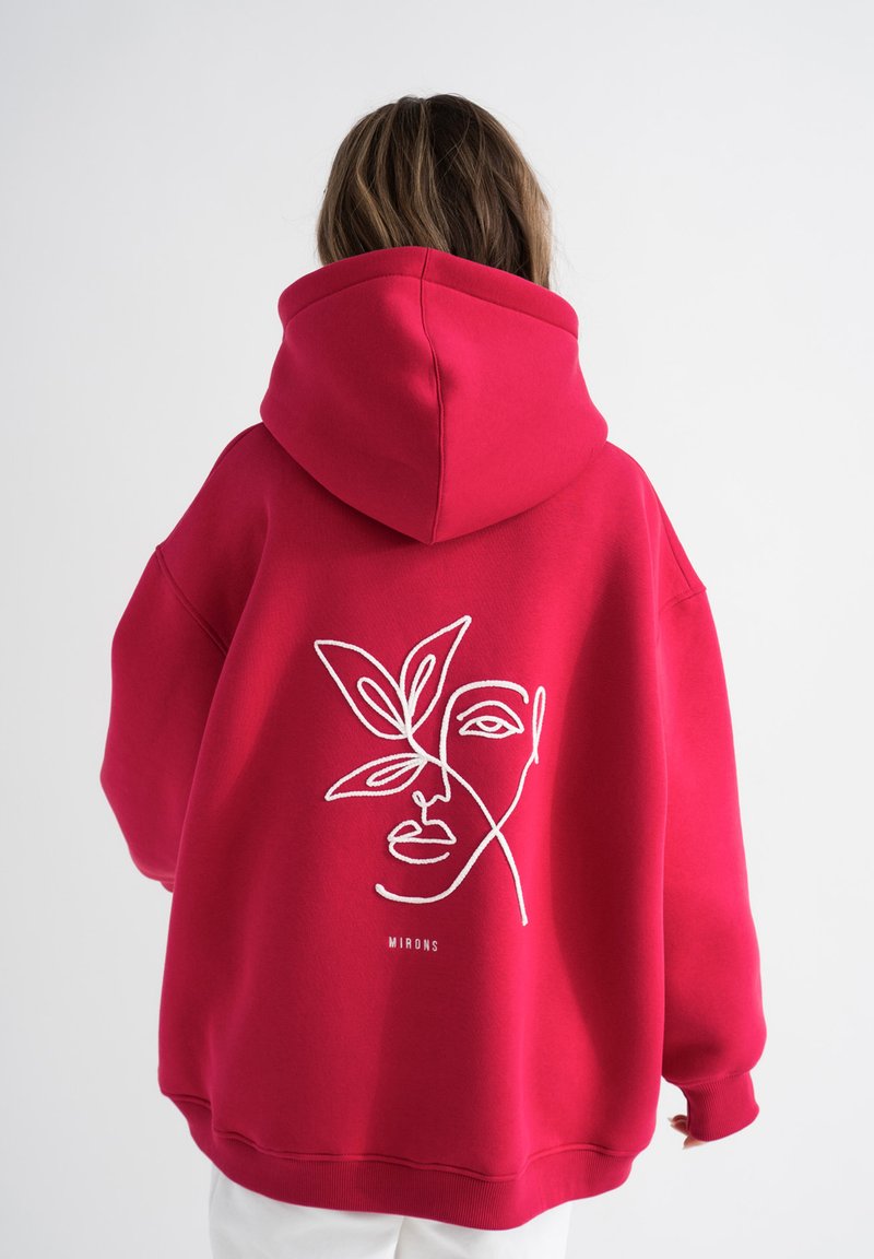 Felpa rossa in tessuto morbido, con un design in linea bianca di un volto e foglie sul retro, con una vestibilità ampia e rilassata.
