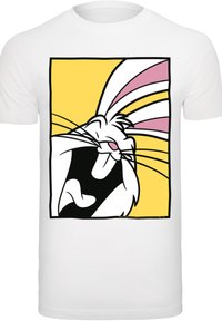 Bílý tričko s potiskem karikatury králíka s široce otevřenou pusou, umístěné na žlutém pozadí. Design zahrnuje růžové a černé akcenty.
