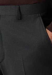 Dunkle, maßgeschneiderte Hosen mit glatter Struktur, flachen Vorderseiten, Taschen und dezenten Falten. Der Bund sitzt bequem an der Taille.