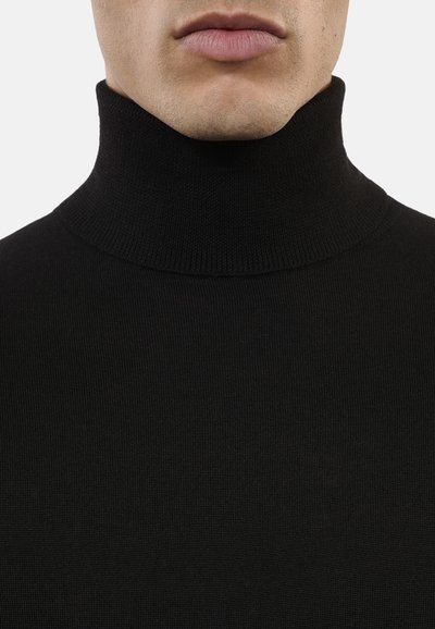 Maglione a collo alto di colore nero realizzato in tessuto a coste. Presenta un collo alto e un design aderente, enfatizzando un aspetto liscio e strutturato.