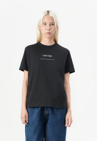 Czarny bawełniany t-shirt z okrągłym dekoltem i krótkimi rękawami. Z przodu znajduje się logo "Calvin Klein" w białym kolorze. Luźny krój.