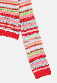 Pull en tricot avec des rayures multicolores en rouge, rose, bleu clair, vert et blanc. Doté d'un motif ajouré et de poignets en forme de vagues.