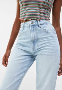 Helle blaue, hochgeschnittene Jeans mit geradem Bein. Aus einem leicht strukturierten Denim gefertigt, mit vorderen Taschen und einem Reißverschluss.