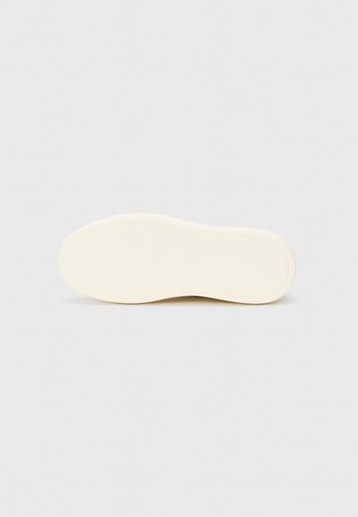 Semelle d'une sneaker, constituée d'un matériau en caoutchouc blanc cassé lisse avec des bords arrondis et une texture minimale, conçue pour le confort et le style.