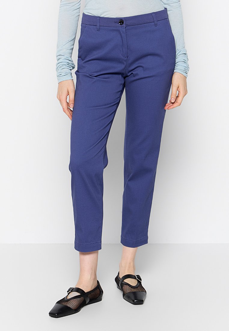 Pantalons sur mesure bleu marine à coupe slim, fermeture à bouton à la taille et poches avant. Portés avec des ballerines en mesh et cuir noires.