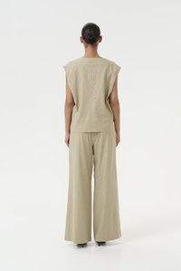Completo beige a due pezzi composto da una maglia morbida con maniche a cappuccio e pantaloni a gamba larga. Il tessuto sembra leggero e testurizzato.