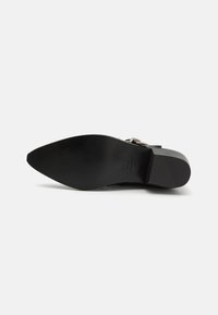 Talpă de pantof din piele neagră, cu vârf ascuțit. Textură netedă, design minimalist, cu imprint al logo-ului și toc plat pentru stabilitate.