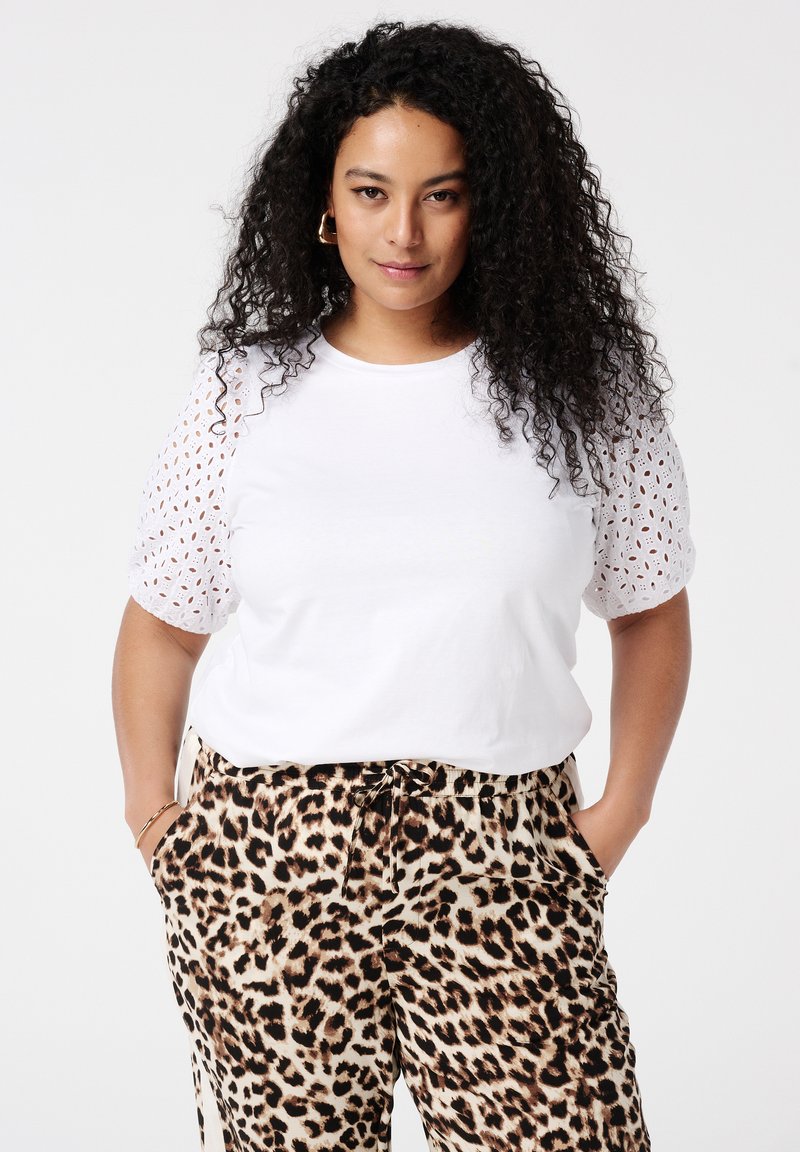 Weißes T-Shirt mit Spitzenverzierung an den Puffärmeln, kombiniert mit Leopardenmuster-Hosen. Weicher Stoff, entspannte Passform und elastischer Bund mit Kordelzug.