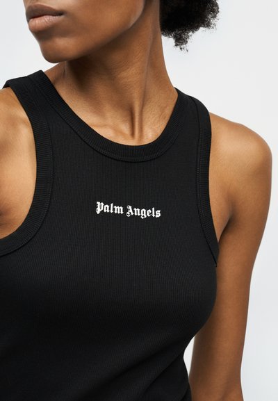 Κοντινό πλάνο ενός ατόμου που φοράει μαύρο αμάνικο τοπ με λευκό κείμενο "Palm Angels" στο κέντρο του στήθους.