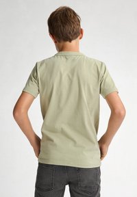Lichtgroene T-shirt met korte mouwen en een ronde hals, gemaakt van zacht materiaal. De achterkant heeft een eenvoudig ontwerp zonder zichtbare graphics.