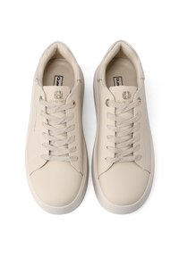 Un paio di sneaker basse beige con lacci beige e una sottile personalizzazione sulla linguetta e sul lato, mostrato dall'alto su uno sfondo bianco.