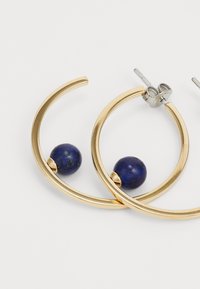 Orecchini a cerchio in oro con un design circolare liscio, caratterizzati da una perla di lapislazzuli blu profondo che accentua ogni cerchio.