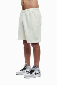 Krémové šortky s elastickým pasem a boční kapsou, zdobené vyšívaným detailem. Doplněné černobílými vysokými teniskami.