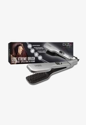 Cepillo alisador de pelo eléctrico plateado con cerdas negras mostrado junto a su embalaje que muestra a una mujer con cabello lacio y castaño.