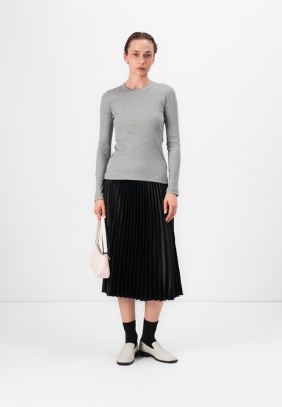 Hall tehnilise särgiga, must plisseeritud midi-seelik, roosa käekott, mustad sokid, valged slip-on jalatsid. Minimalistlik disain, vastandlikud tekstuurid.