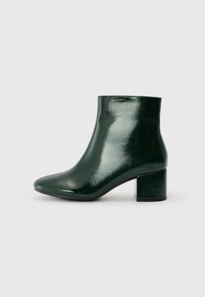 Grønne patentlæder ankelstøvler med rund tå og blokhæl. Glat tekstur med en blank finish, der viser et moderne design.
