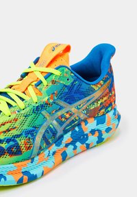 Barevná běžecká bota s neonově zelenými tkaničkami, modro-oranžov�ě vzorovanou podrážkou a jasně oranžovým jazykem se znakem Asics.