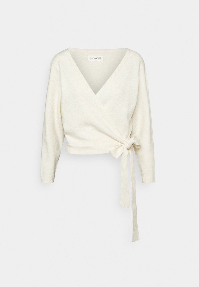 Pull cache-cœur tricot couleur crème avec manches longues et nœud sur le côté sur un fond clair uni.