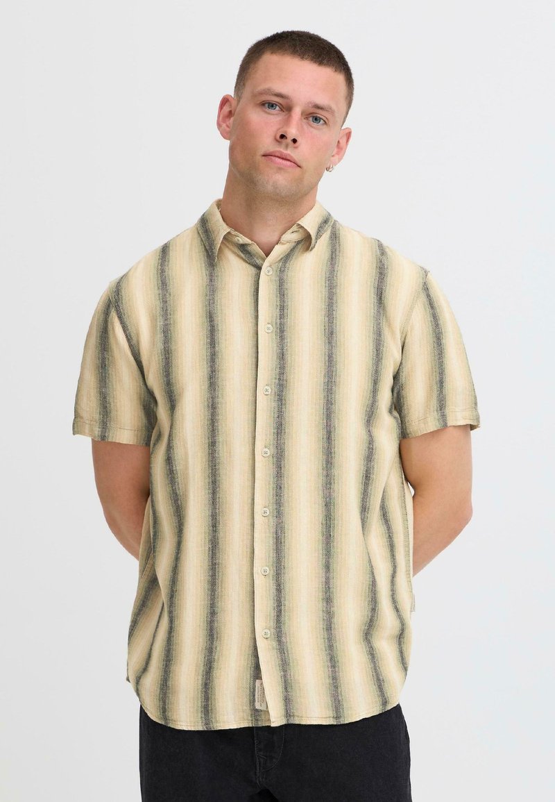 Korte mouwen overhemd in beige met verticale groene en bruine strepen. Lichtgewicht stof, kraag en een loszittend ontwerp.