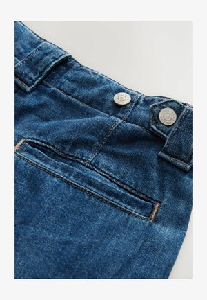 Jean en denim bleu foncé, avec une texture lisse, des coutures contrastées, deux boutons métalliques et une petite poche arrière.