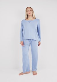 Light blue pajama set featuring a long-sleeve V-neck top with lace inset and matching pants with an elastic waistband, made from soft fabric.
