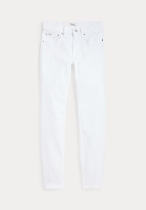 Fehér, karcsúsított szabású farmer öt zsebbel, övtartóval és gombos lezárással, világos háttéren, laposan elhelyezve.