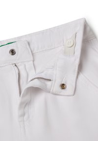 Pantalones cortos de denim blanco con cremallera, cierre de botón a presión y detalles de costura. Presenta una etiqueta verde de contraste en la parte interior del cinturón.