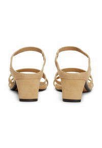 Sandalias de tacón de ante beige con tacón cuadrado, punta abierta y correas entrecruzadas en la parte trasera para un ajuste seguro.