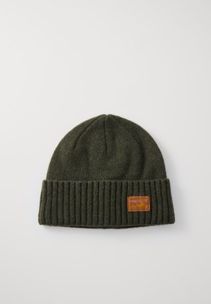 Gorro de punto verde oscuro con un puño acanalado y una etiqueta de cuero marrón con gráficos de montaña, hecho de una tela suave.