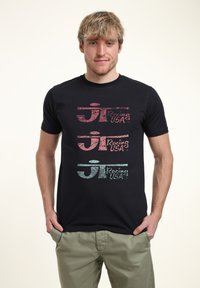 Schwarzes Baumwoll-T-Shirt mit drei übereinander gestapelten "Racing USA"-Logos in Rot, Pink und Hellblau mit einer strukturierten Oberfläche.