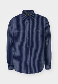 Mörkblå knäppskjorta med vertikala vita ränder, två bröstfickor med knappar och en "Lee"-märkesetikett på vänstra fickan.