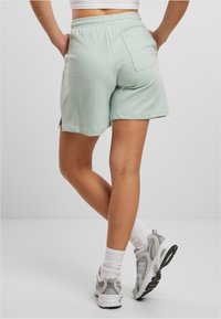 Mint green shorts with an elastic waistband, side slits, and a back pocket, paired with gray and white athletic shoes and crew socks.