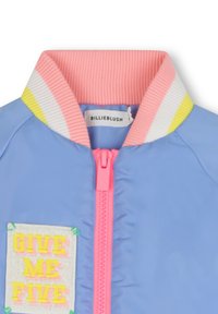 Blauwe bomberjack met een roze en gele gestreepte kraag, met een geborduurde patch waarop "GIVE ME FIVE" staat in felle kleuren.