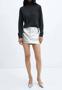 Pull à col roulé gris, minijupe argentée métallique et escarpins argentés à bout pointu. Texture lisse, coupe ajustée et style minimaliste.