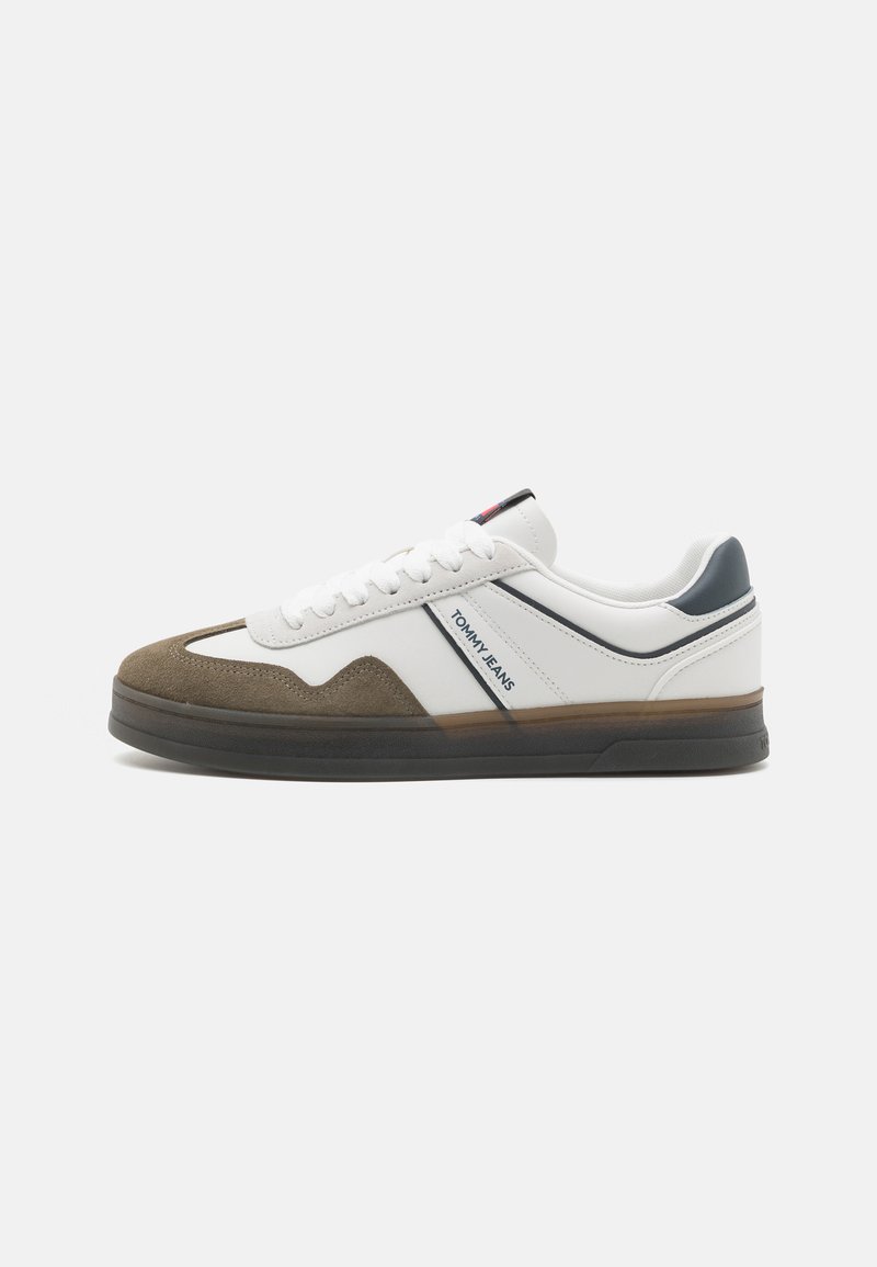 Hvide og brune sneakers med en tekstureret ruskinds-tå, glat læderkrop og en mørk gummisål. Har blå og røde accenter samt branding.