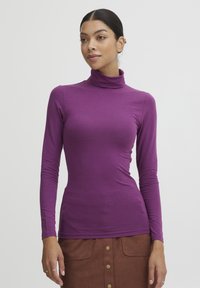 Lilla langærmet turtleneck skjorte i et let, strækbart stof; tætsiddende silhuet med glat tekstur og høj halsudskæring.