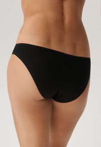 Czarny materiałowy dół bikini o gładkim wykończeniu, z średnim poziomem zakrycia i niskim stanem. Proste, bezszwowe krawędzie.