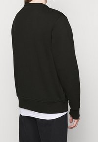 Sudadera nera con scollo a girocollo, polsini e orlo a costine, realizzata in materiale morbido; esposta dal retro con dettagli minimi.