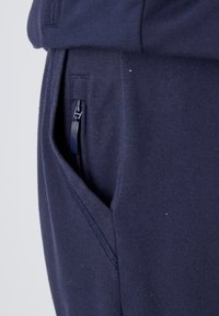 Pantalons de jogging bleu marine en tissu doux, avec une poche zippée sur le côté et une texture sans coutures pour le confort.