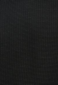 Μαύρο υφασμάτινο υλικό με υφή που διαθέτει ριγωτό σχέδιο και ήπιες παραλλαγές χρώματος, προσδίδοντας μια δομημένη και ανθεκτική εμφάνιση.