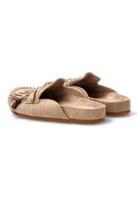 Sandalias de ante beige sin hebillas con una parte superior texturizada que presenta costuras decorativas y una suela plana de goma, diseñadas para la comodidad y el uso casual.